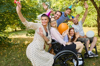 Outdoor birthday party celebration with diverse friends including a woman using wheelchair