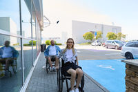 People using wheelchairs enjoying a bright day outside a modern building