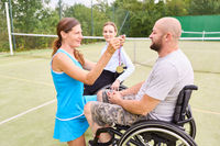 Tennis player awarding a medal to a happy wheelchair athlete outdoors