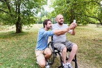 Two friends in wheelchairs taking a selfie in a park, showcasing inclusivity and joy