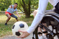 Person in wheelchair playing soccer with friends in a park, exemplifying inclusion and activity