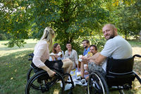 Group of friends enjoying a picnic in the park, with individuals who use wheelchairs participating fully